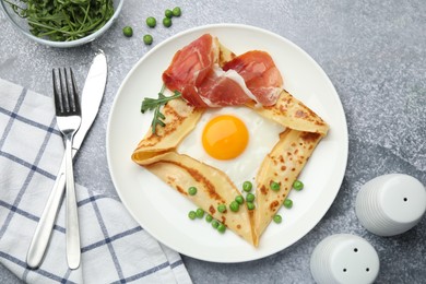 Photo of Delicious crepe with egg, bacon, arugula and green peas on grey table, flat lay