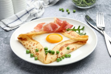 Photo of Delicious crepe with egg, bacon, arugula and green peas on grey table, closeup