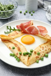 Photo of Delicious crepe with egg, bacon, arugula and green peas on grey table, closeup