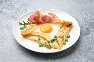 Photo of Delicious crepe with egg, bacon, arugula and green peas on grey table, closeup