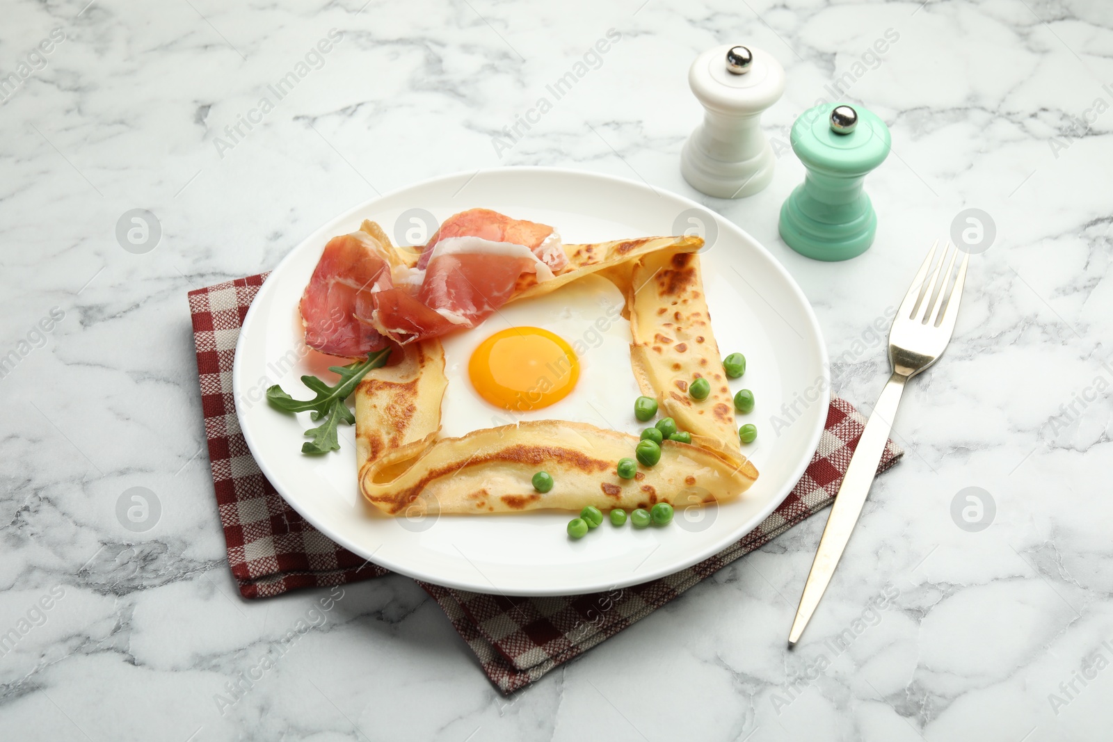 Photo of Delicious crepe with egg, bacon, arugula and green peas on white marble table