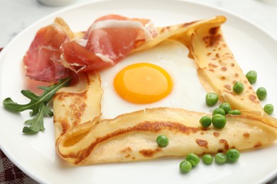 Photo of Delicious crepe with egg, bacon, arugula and green peas on plate, closeup