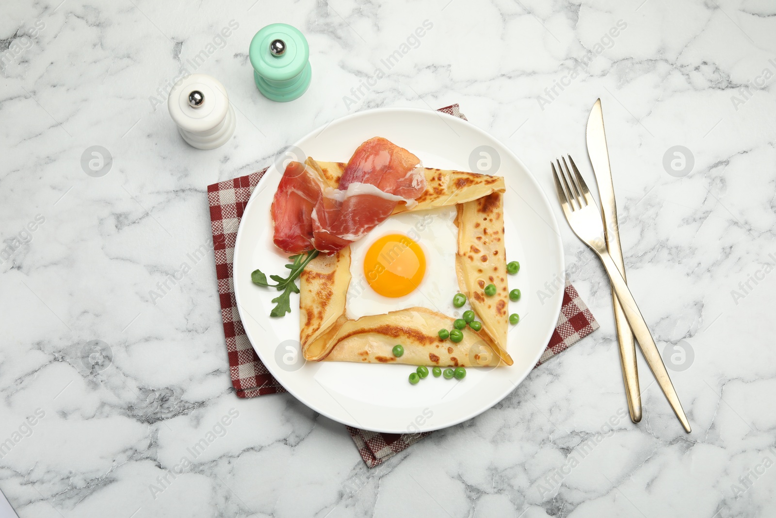 Photo of Delicious crepe with egg, bacon, arugula and green peas on white marble table, flat lay