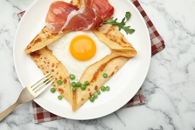 Photo of Delicious crepe with egg, bacon, arugula and green peas on white marble table, top view