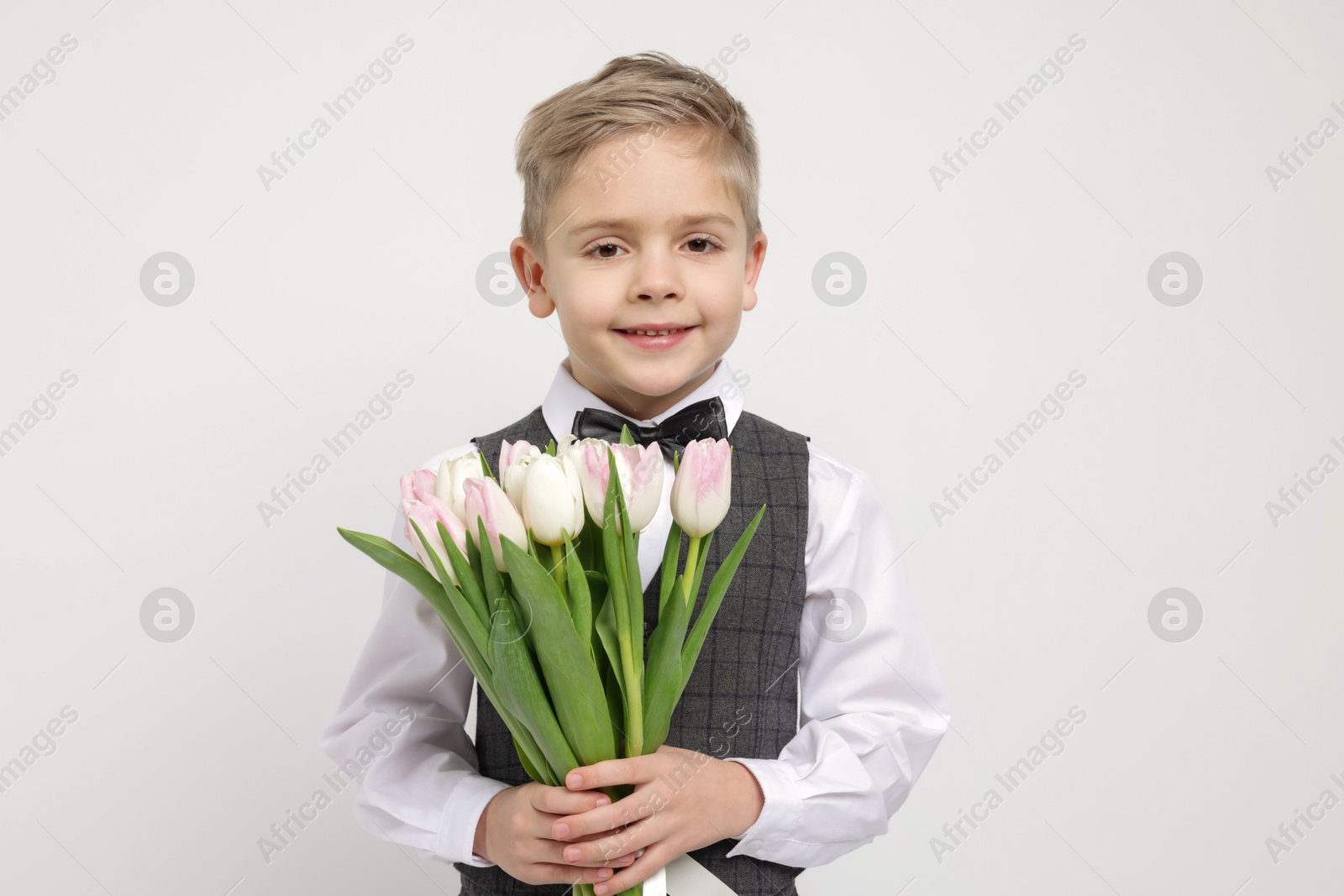 Photo of Cute little boy with bouquet of tulips on white background