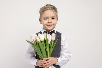 Cute little boy with bouquet of tulips on white background