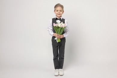 Photo of Cute little boy with bouquet of tulips on white background