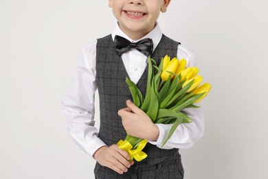 Little boy with bouquet of tulips on white background, closeup