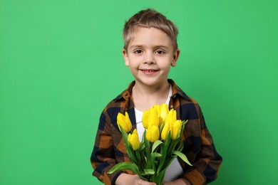 Photo of Cute little boy with bouquet of tulips on green background