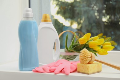 Photo of Spring cleaning. Detergents, supplies and tulips on windowsill indoors