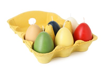 Photo of Colorful egg-shaped candles in carton isolated on white. Easter decor