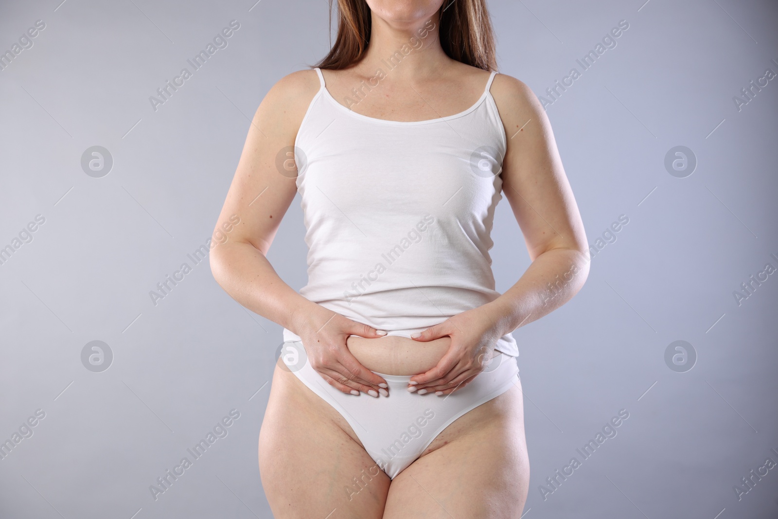 Photo of Woman in underwear on light grey background, closeup. Cellulite problem