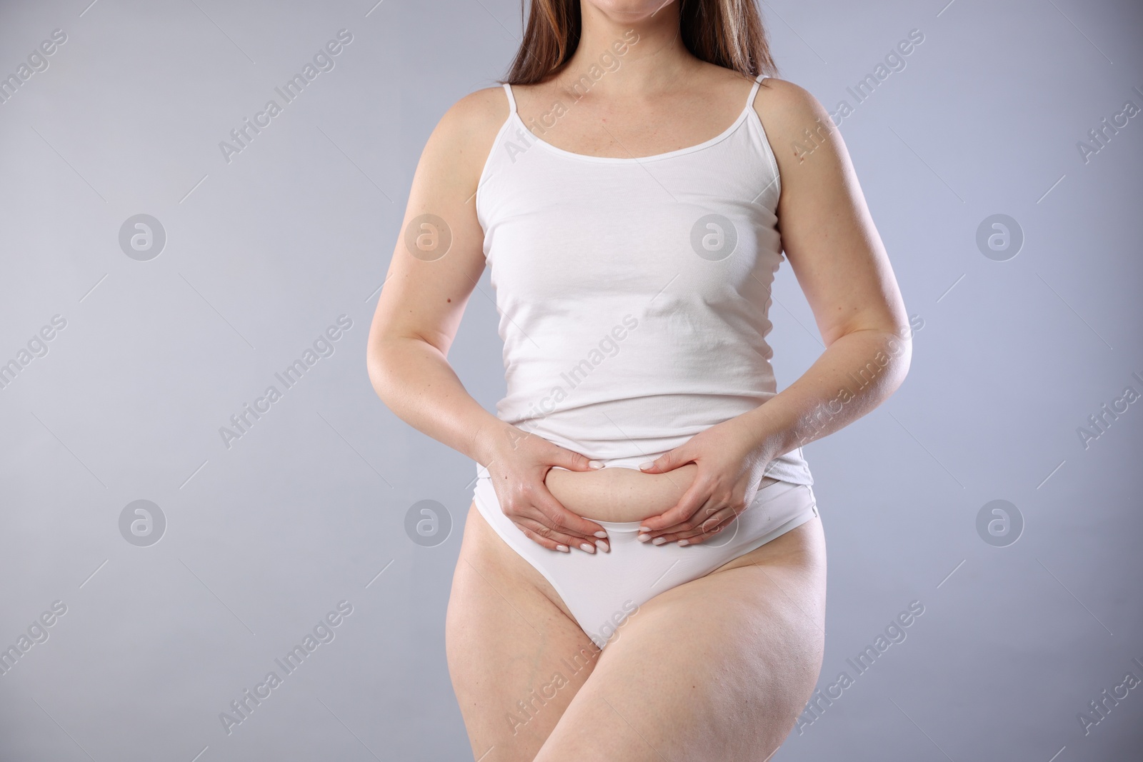 Photo of Woman in underwear on light grey background, closeup. Cellulite problem