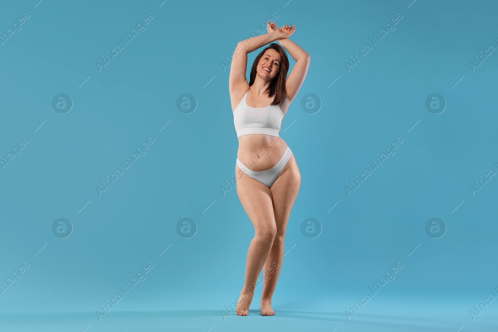 Photo of Woman in underwear on light blue background. Cellulite problem