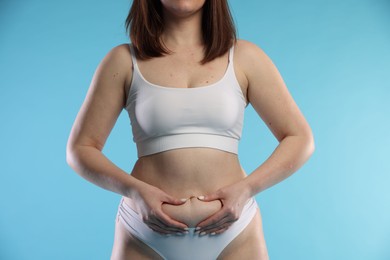 Photo of Woman with cellulite on light blue background, closeup