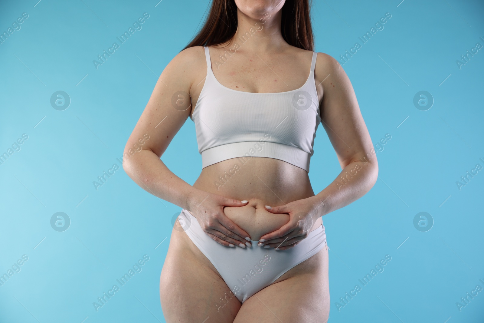 Photo of Woman with cellulite on light blue background, closeup