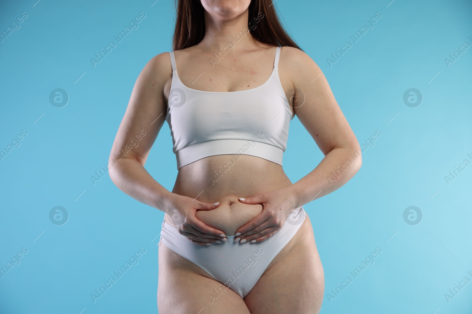 Photo of Woman with cellulite on light blue background, closeup