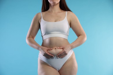 Photo of Woman with cellulite on light blue background, closeup