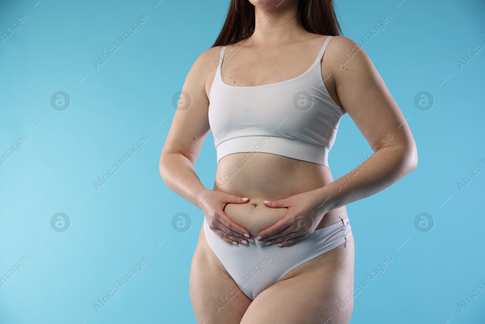 Photo of Woman with cellulite on light blue background, closeup. Space for text