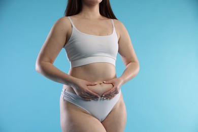 Photo of Woman with cellulite on light blue background, closeup