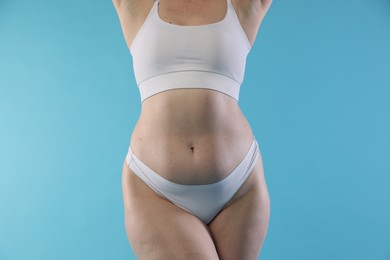 Photo of Woman with cellulite on light blue background, closeup