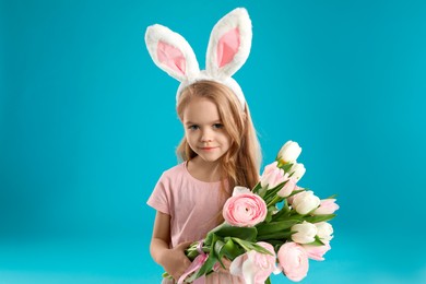 Photo of Cute little girl with bunny ears and spring flowers on light blue background. Easter celebration