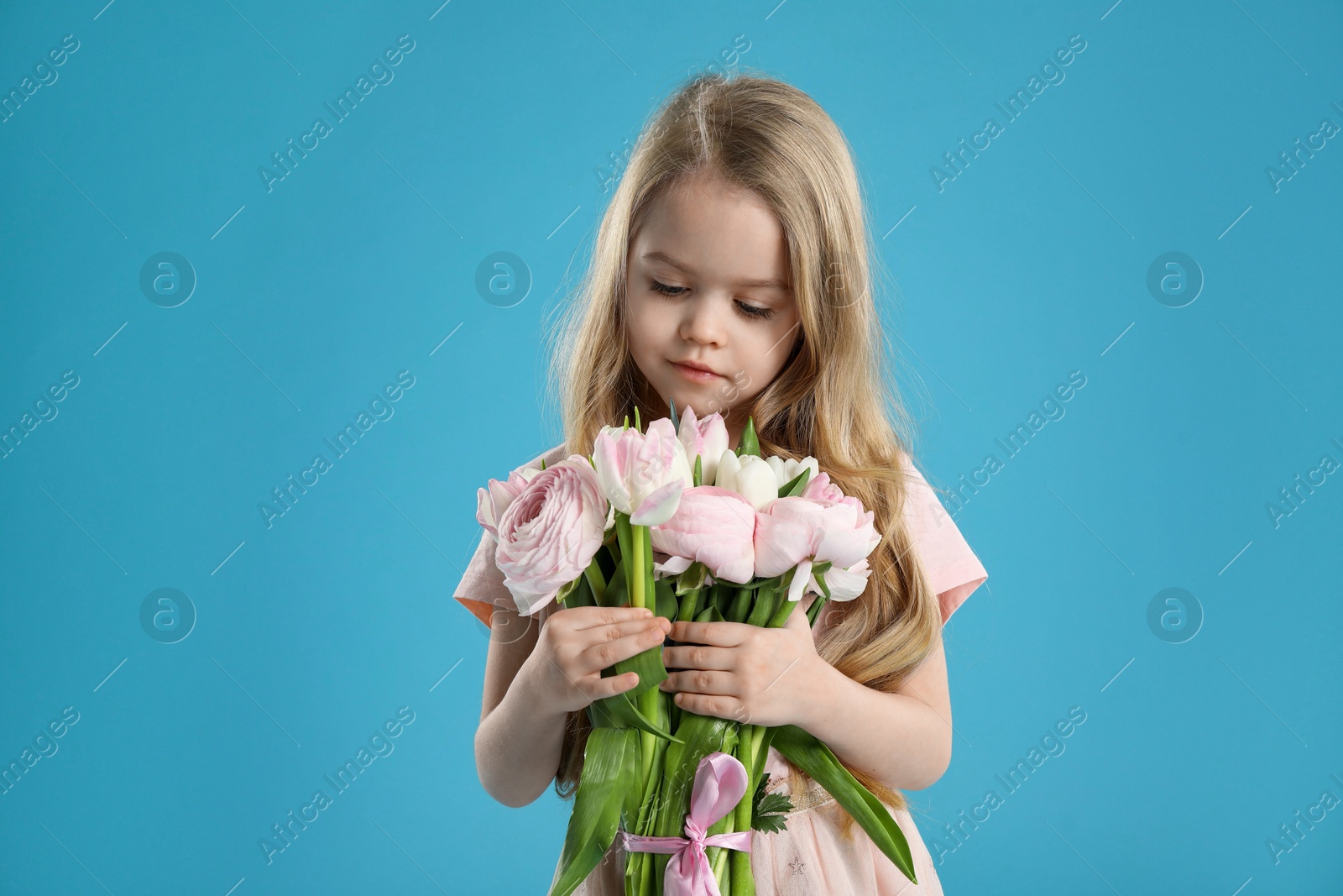 Photo of Cute little girl with bouquet of beautiful spring flowers on light blue background