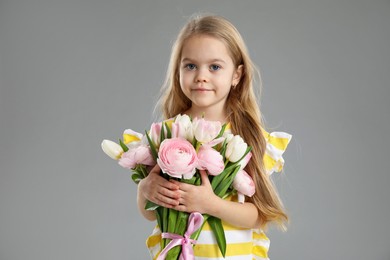 Photo of Cute little girl with bouquet of beautiful spring flowers on gray background