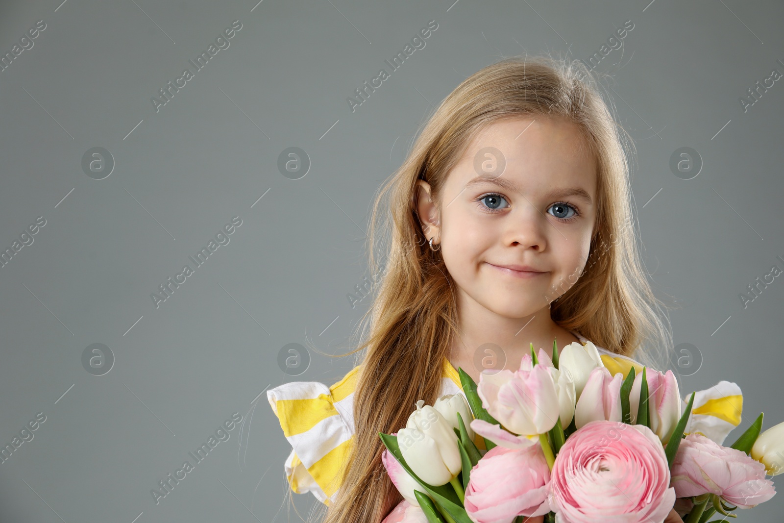 Photo of Cute little girl with bouquet of beautiful spring flowers on gray background, space for text