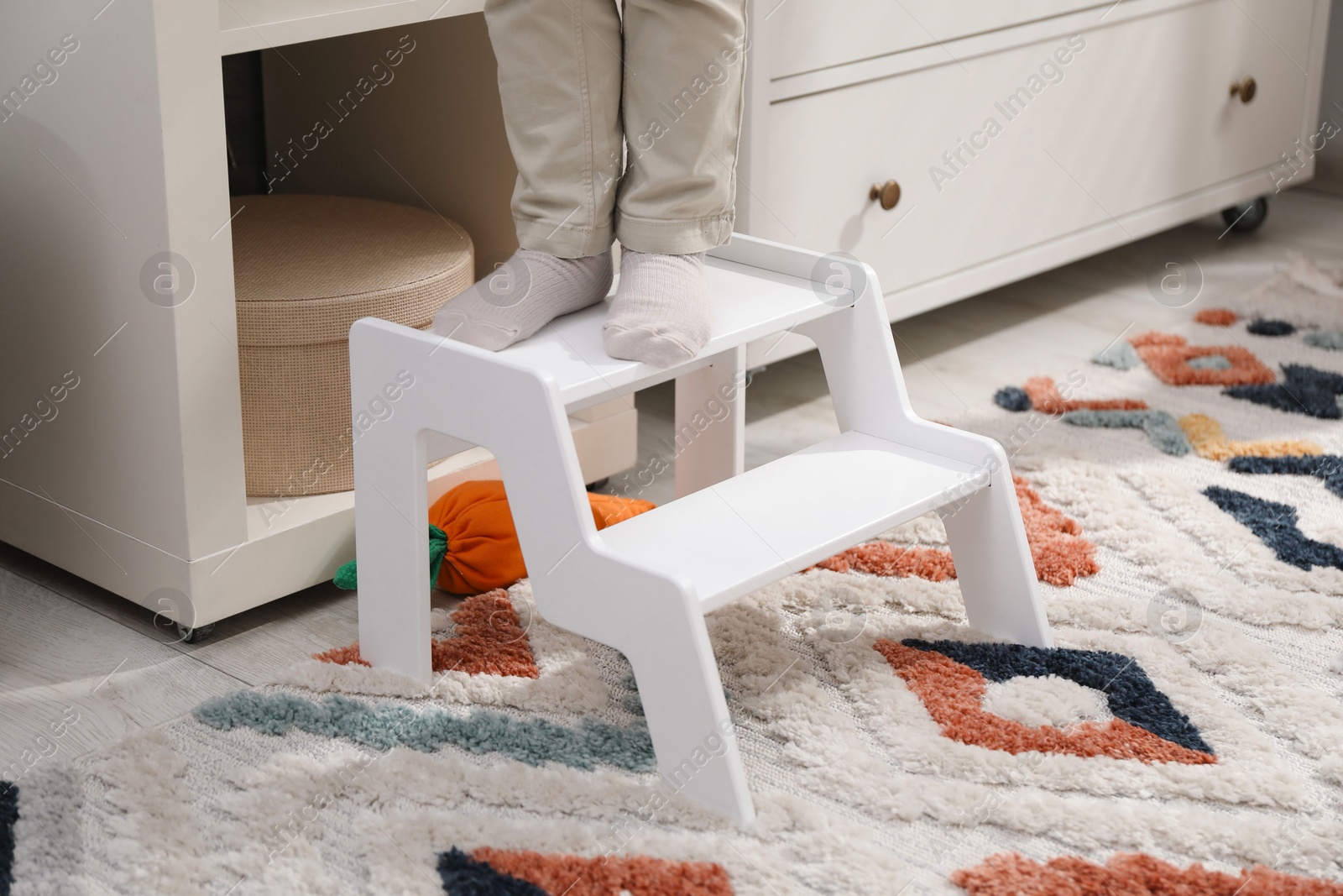 Photo of Little boy standing on step stool at home, closeup