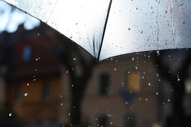 Photo of Open umbrella under pouring rain outdoors, closeup