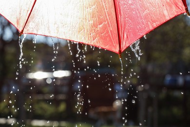 Photo of Open red umbrella under pouring rain outdoors, closeup