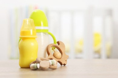 Photo of Feeding bottles with milk and toys on wooden table indoors. Space for text