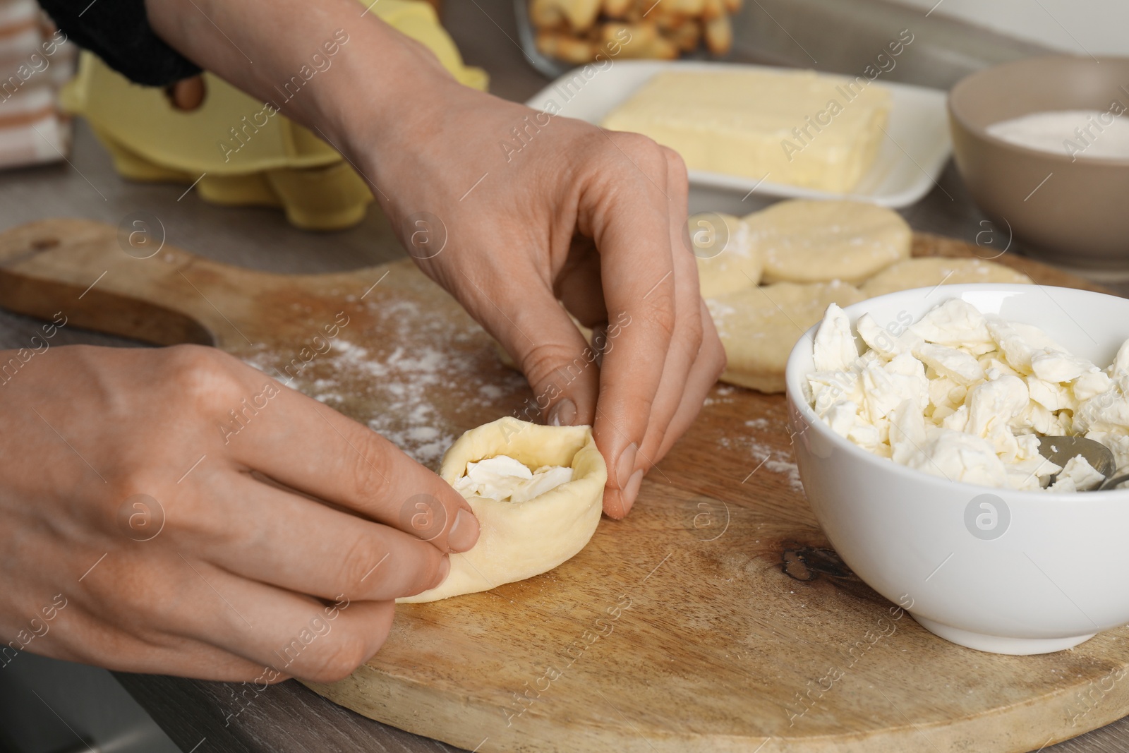 Photo of Woman making pirozhki (stuffed pastry pies) with cottage cheese at table, closeup