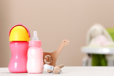 Photo of Feeding bottles with milk and toys on white wooden table indoors, space for text