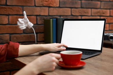 Photo of Woman working with laptop at table in office, closeup