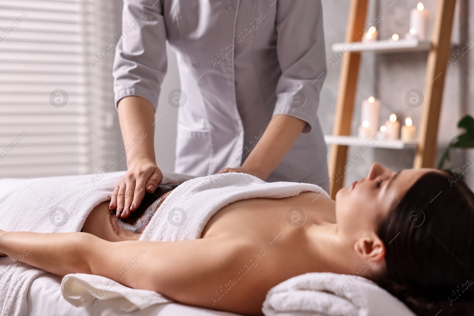 Photo of Woman undergoing chocolate body wrap treatment in spa salon