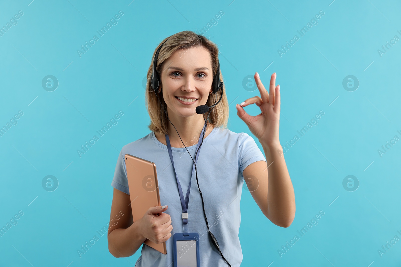 Photo of Technical support call center. Smiling operator with tablet showing ok gesture on light blue background