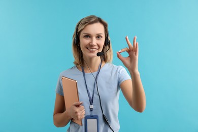 Photo of Technical support call center. Smiling operator with tablet showing ok gesture on light blue background