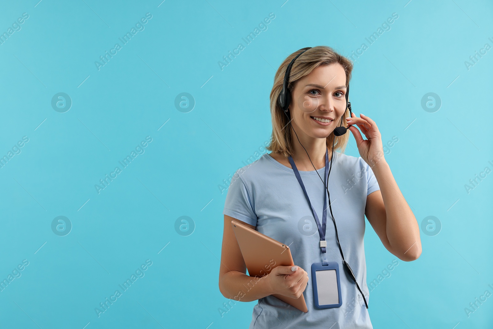 Photo of Technical support call center. Smiling operator with tablet on light blue background. Space for text