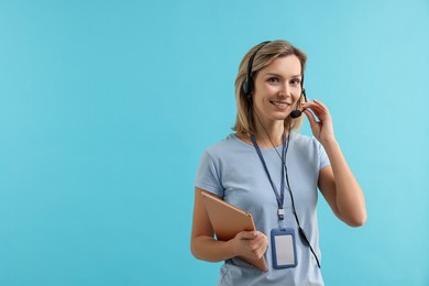 Photo of Technical support call center. Smiling operator with tablet on light blue background. Space for text