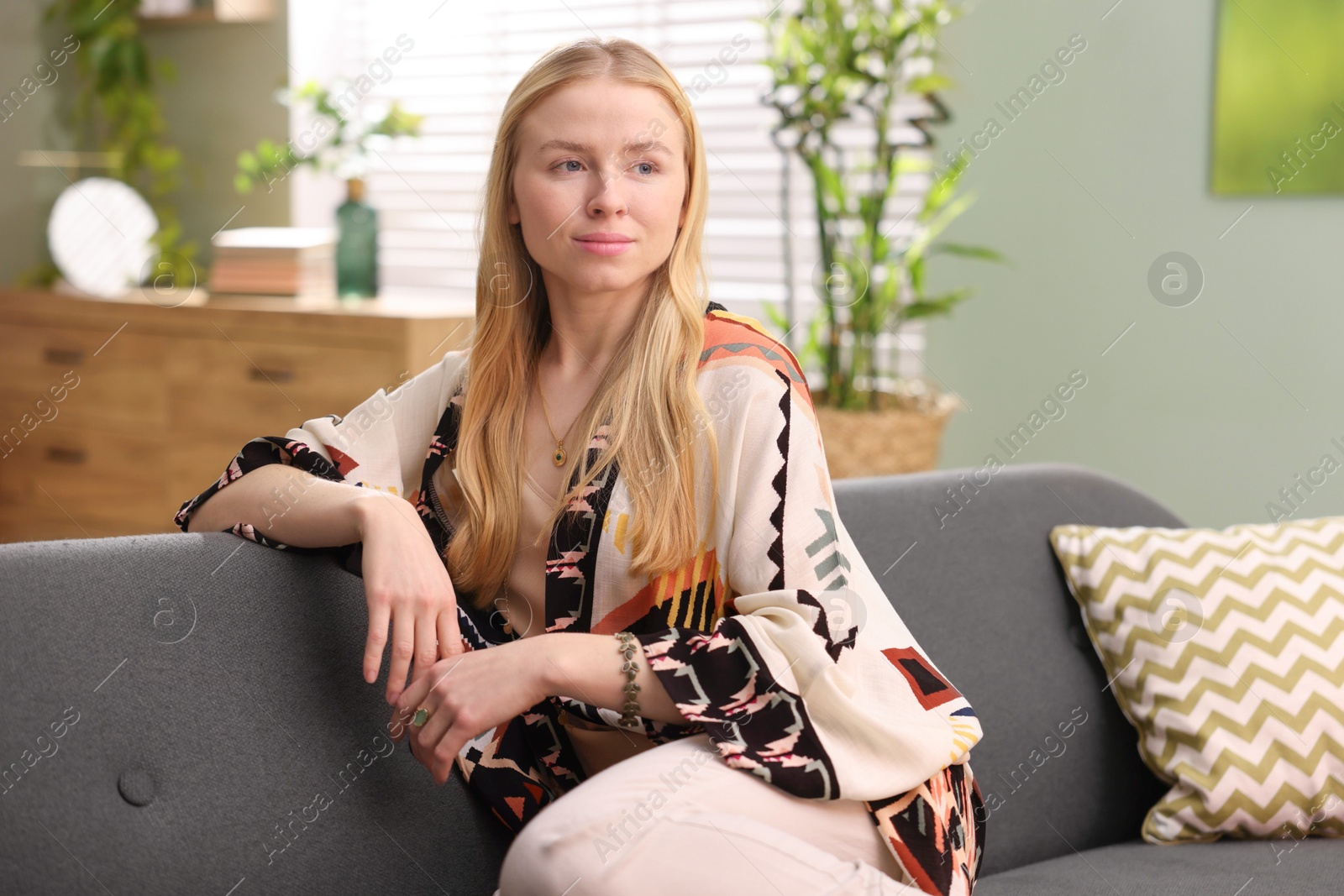 Photo of Feng shui. Young woman sitting on couch at home