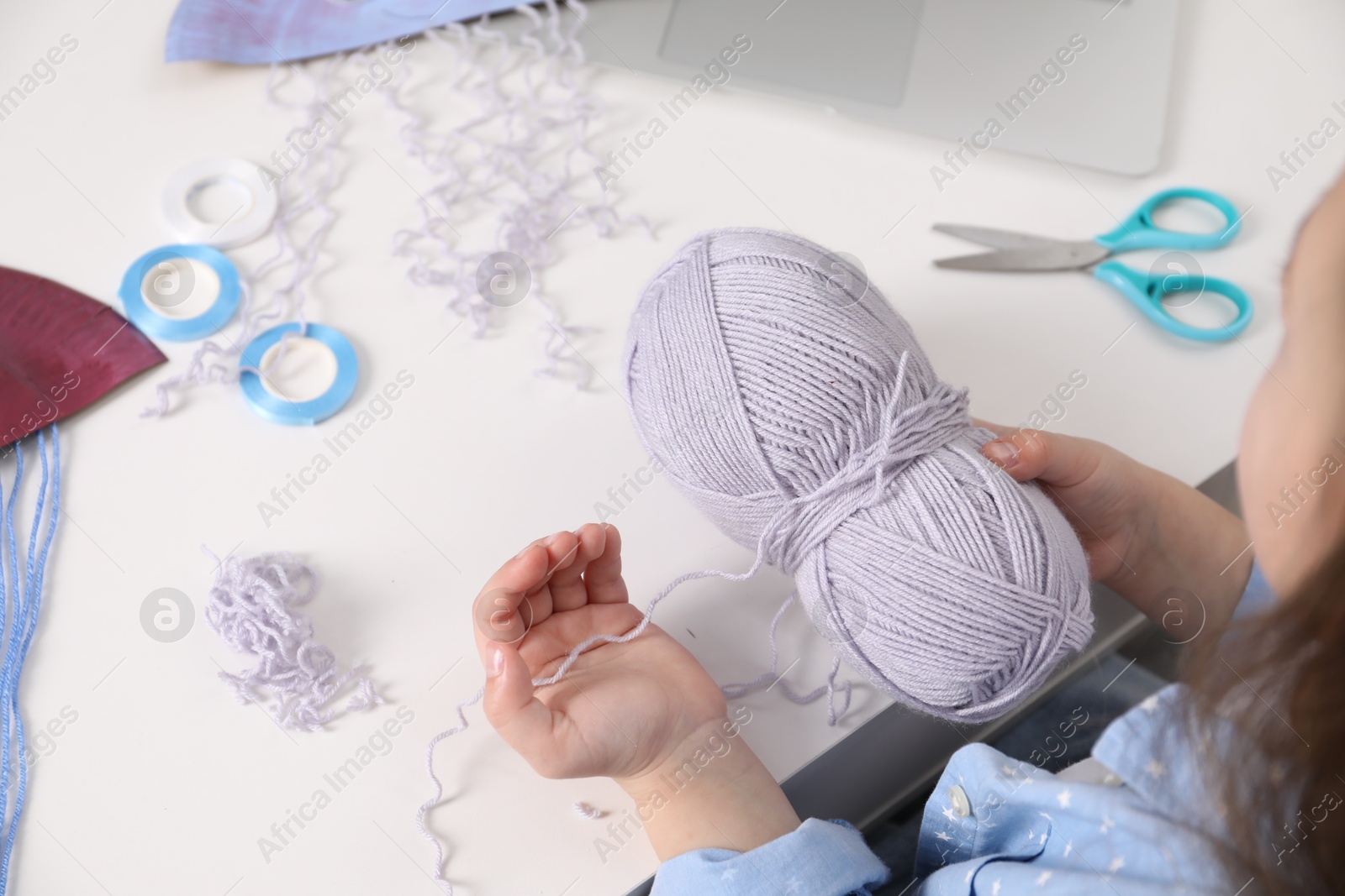 Photo of Little girl making craft at white table. Child creativity