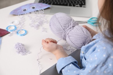 Photo of Little girl making handmade jellyfish by craft tutorial video at white table. Child creativity