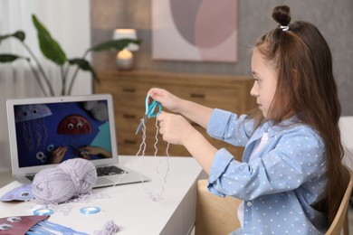 Photo of Little girl making handmade jellyfish by craft tutorial video at home. Child creativity