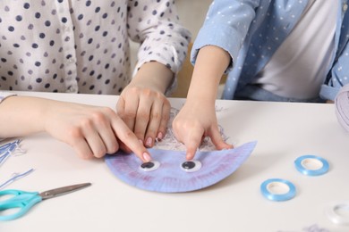 Photo of Woman and little girl making paper jellyfish at home, closeup. Child handmade craft