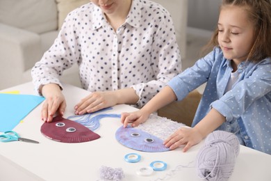 Photo of Woman and little girl making paper jellyfish at home, closeup. Child handmade craft