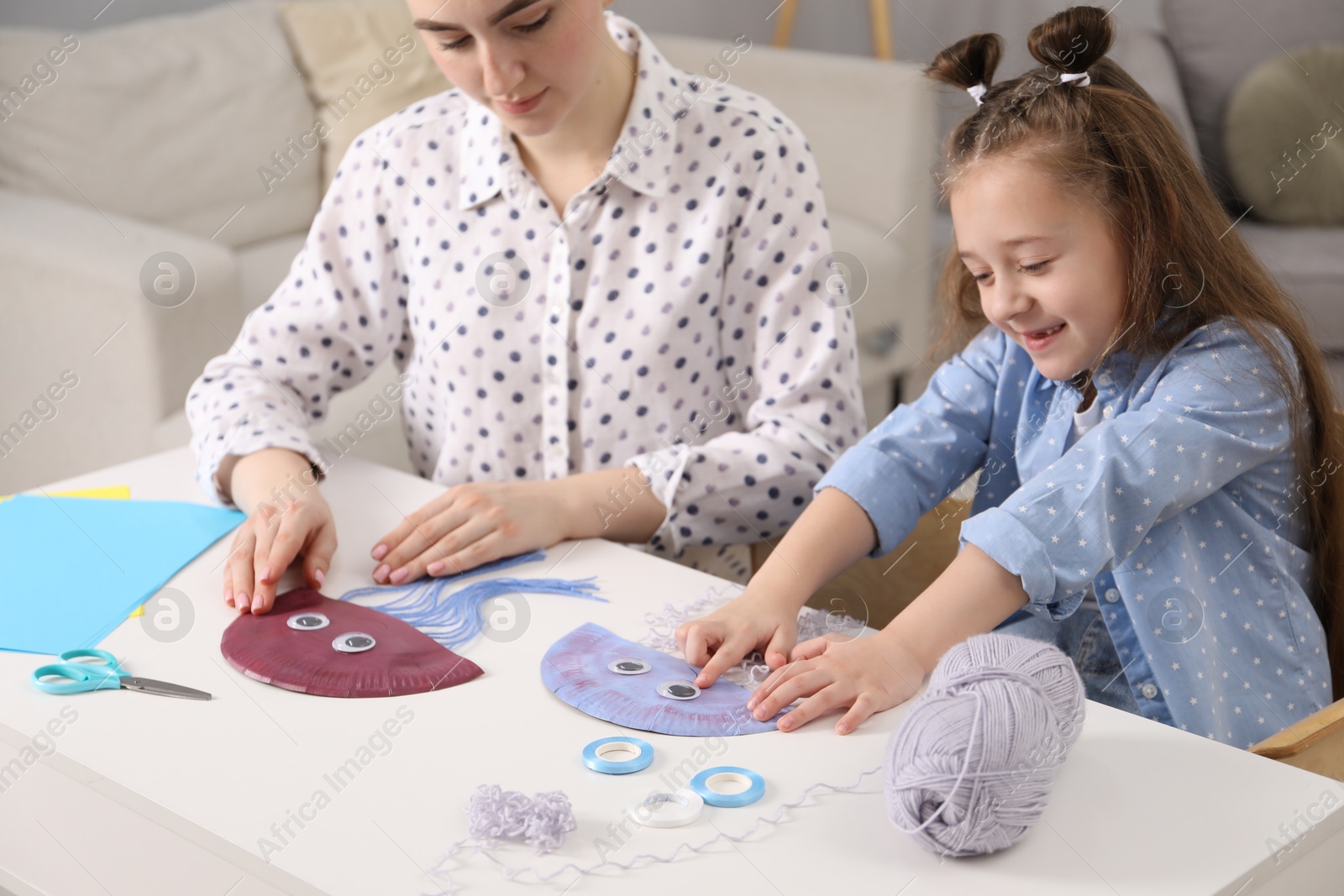 Photo of Woman and little girl making paper jellyfish at home. Child handmade craft