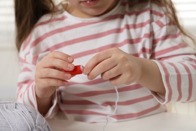 Photo of Little girl making craft at white table indoors, closeup. Child creativity and handmade handicraft