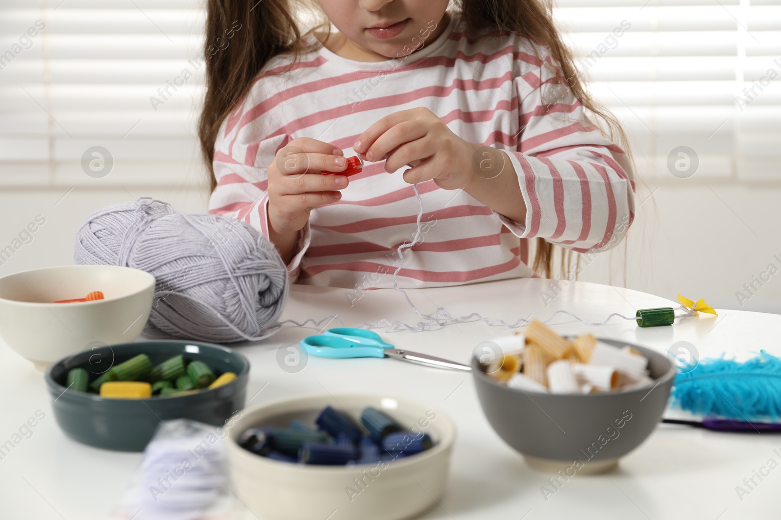 Photo of Little girl making craft at white table indoors, closeup. Child creativity and handmade handicraft